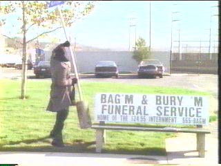 [hooded figure grabbing bus-stop pole]