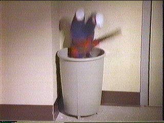 [doll flying into wastebasket]